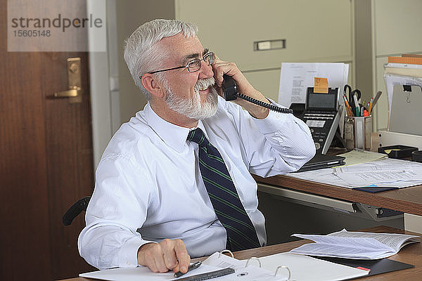 Mann mit Muskeldystrophie im Rollstuhl am Telefon in seinem Büro