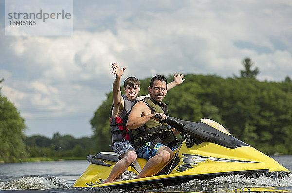 Junger Mann mit Down-Syndrom fährt mit seinem Freund auf einem Jet-Ski in einem See