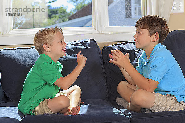Hörgeschädigte Jungen  die auf ihrer Couch in amerikanischer Gebärdensprache Wo  Fußball gebärden