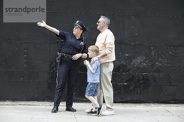 Eine Polizeibeamtin dirigiert einen älteren Mann mit einem Jungen.