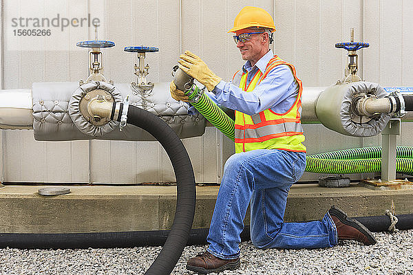 Ingenieur in einem Elektrizitätswerk bei der Prüfung eines Anschlussschlauchs in der Nähe eines Wasserspeichers