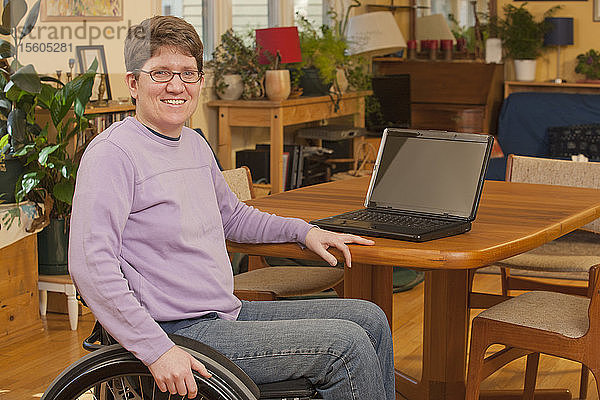 Frau mit Multipler Sklerose an einem Tisch mit Laptop