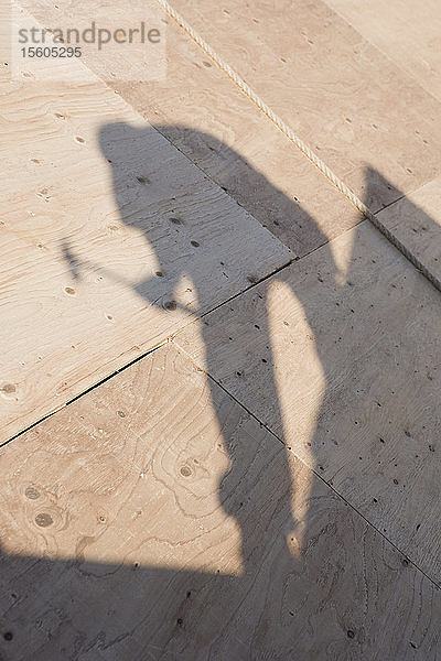 Schatten eines Zimmermanns auf dem Dach eines im Bau befindlichen Hauses