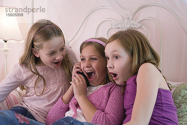 Drei junge Mädchen hören am Telefon zu
