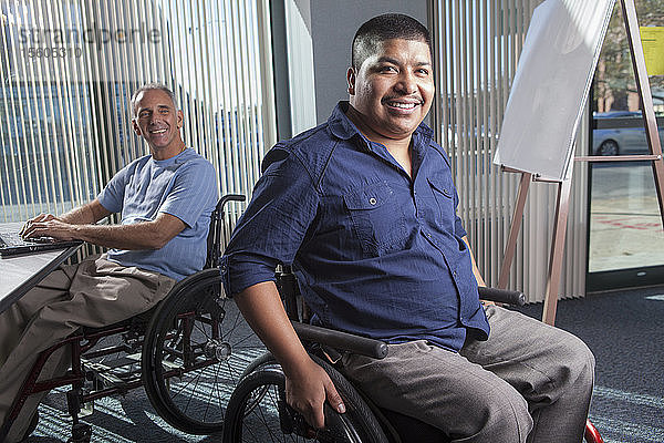 Zwei Männer mit Rückenmarksverletzungen arbeiten in einem Büro