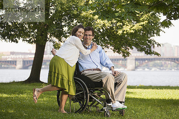 Schwangere Frau umarmt ihren Mann  der im Rollstuhl sitzt und eine Rückenmarksverletzung hat