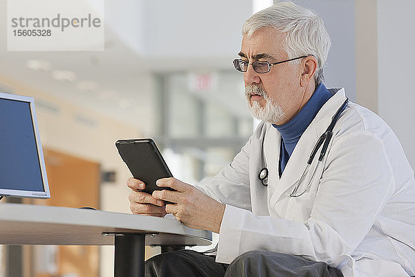 Arzt mit Muskeldystrophie schaut auf sein Tablet