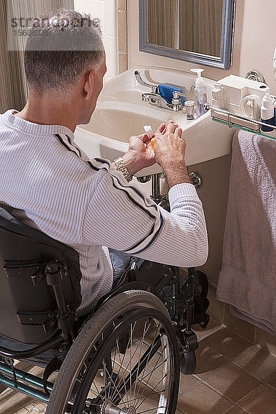 Mann mit Rückenmarksverletzung im Rollstuhl nimmt Medikamente ein