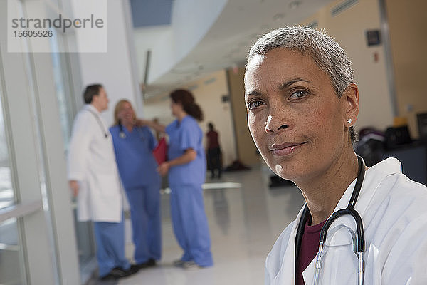 Porträt einer Ärztin mit ihren Kollegen im Hintergrund