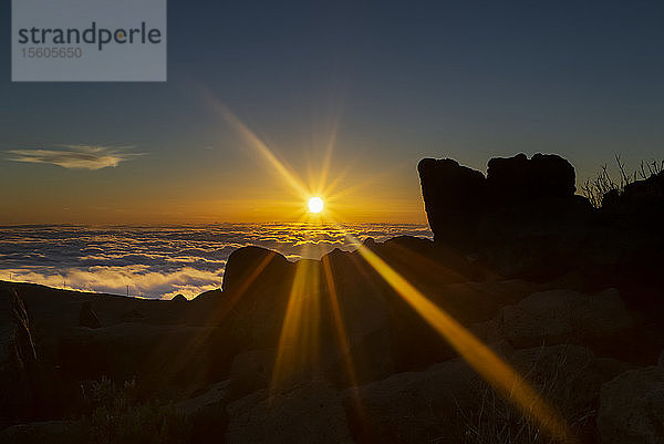 Haleakala bei Sonnenuntergang mit dramatischen goldenen Sonnenstrahlen  die hell über Felsen und Wolken scheinen; Maui  Hawaii  Vereinigte Staaten von Amerika