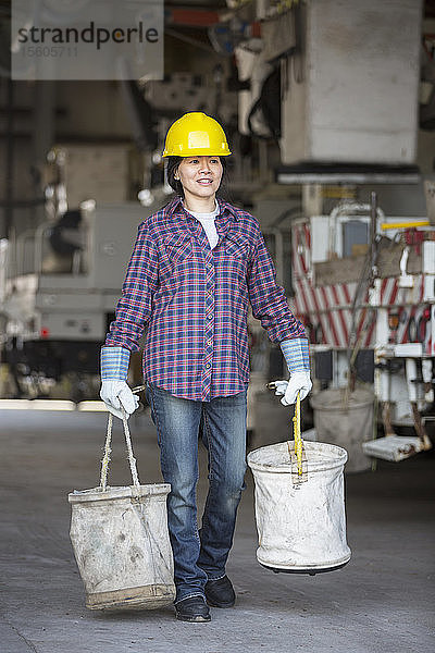 Eine Ingenieurin bereitet in einer Werkstatt in der Nähe eines Lastwagens einen Eimer aus Segeltuch vor.