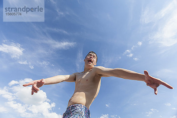 Junger Mann mit Down-Syndrom spielt auf einem Steg vor einem Himmel