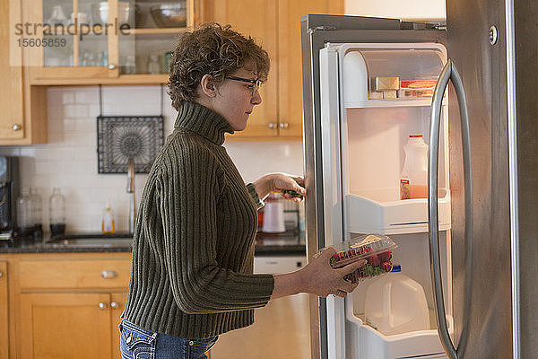 Frau mit Sjogren-Larsson-Syndrom legt Erdbeeren in den Kühlschrank