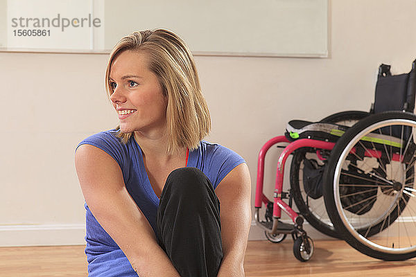 Porträt einer jungen Frau mit einer Rückenmarksverletzung und ihrem Rollstuhl in einem Yogastudio