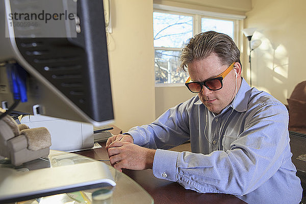 Ein Mann mit angeborener Blindheit nutzt Hilfsmittel an seinem Computer  um zuzuhören