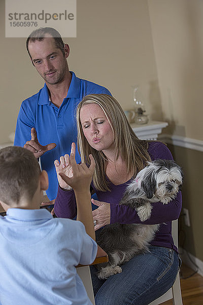 Familie mit Hörbehinderung sagt in amerikanischer Zeichensprache Ich liebe dich mit einem Hund zu Hause