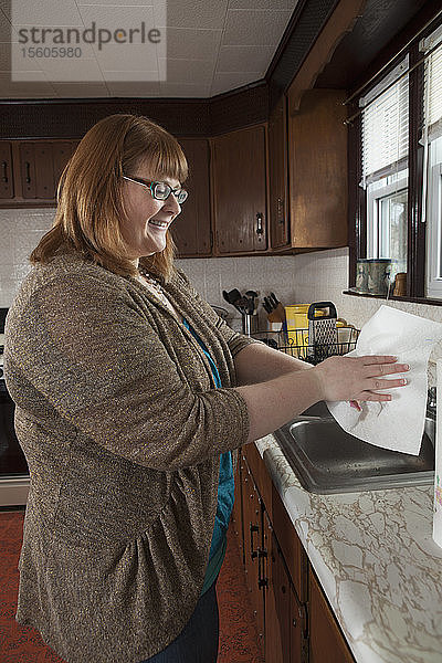Eine blinde Frau wäscht sich in ihrer Küche die Hände