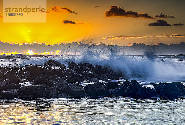 Goldener Sonnenaufgang über dem Lydgate Park und dem Ozean an der Küste von Kauai mit einem silhouettierten Wellenbrecher; Kapaa  Kauai  Hawaii  Vereinigte Staaten von Amerika