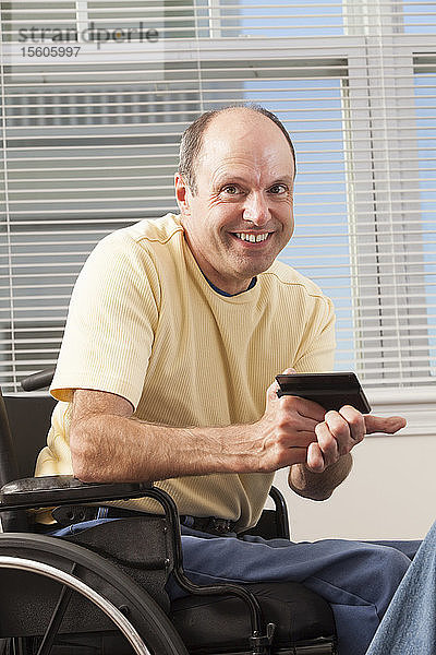 Mann mit Friedreich-Ataxie im Rollstuhl beim Lesen eines Smartphones