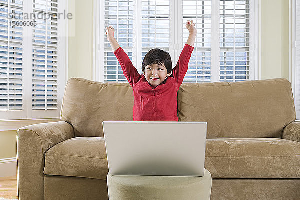 Blick auf einen fröhlichen Jungen mit einem Laptop.