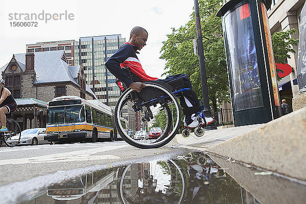 Mann im Rollstuhl  der an Spinaler Meningitis leidet  fährt über einen Bordstein