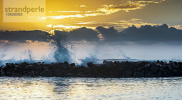 Goldener Sonnenaufgang über dem Lydgate Beach und dem Meer an der Küste von Kauai mit einem Wellenbrecher als Silhouette; Kapaa  Kauai  Hawaii  Vereinigte Staaten von Amerika