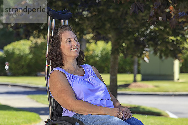 Frau mit Spina bifida entspannt sich im Rollstuhl mit Krücken