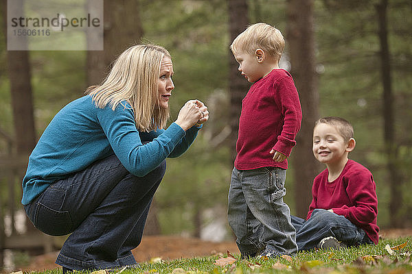 Frau  die das Wort Hurt in amerikanischer Gebärdensprache gebärdet  während sie mit ihrem Sohn in einem Park kommuniziert