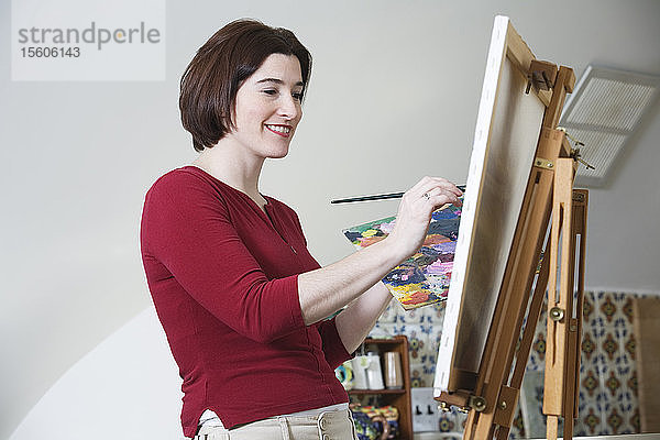 Seitenansicht einer lächelnden jungen Frau beim Malen.