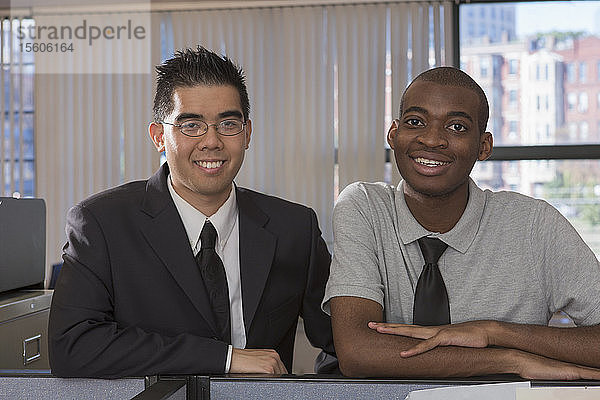 Porträt von zwei lächelnden Männern mit Autismus in einem Büro