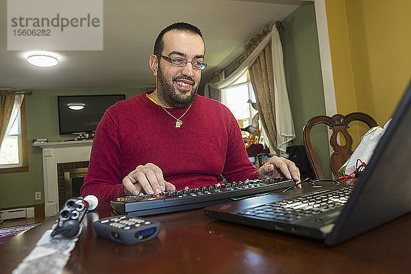 Mann mit Sehbehinderung an seiner Tastatur mit einem Bildschirmlesegerät