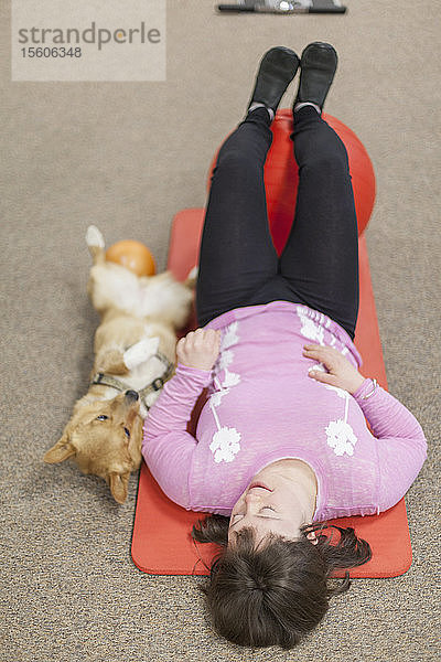 Mädchen mit Down-Syndrom trainiert auf einer Yogamatte mit ihrem Hund