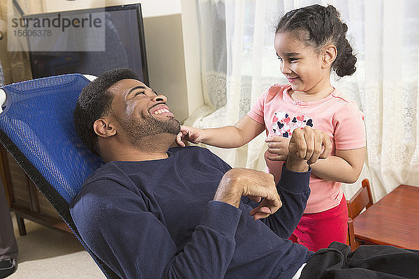 Afroamerikanischer Mann mit Cerebralparese hat Spaß mit seiner Tochter zu Hause Cerebralparese
