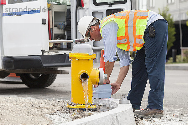 Ein Ingenieur des Ministeriums für öffentliche Arbeiten entleert einen Hydranten und bereitet die Entnahme einer Wasserprobe vor