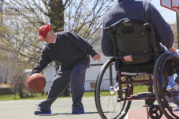 Ein Vater mit einer Rückenmarksverletzung und sein Sohn mit Down-Syndrom spielen Basketball in einem Park