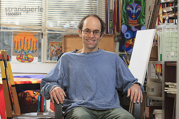 Mann mit Asperger-Syndrom sitzt in seinem Kunstatelier