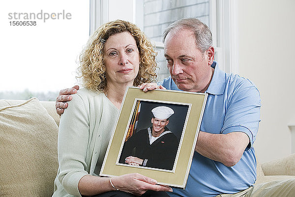 Porträt eines reifen Paares  das ein Bild seines Sohnes hält  der beim Militär arbeitet