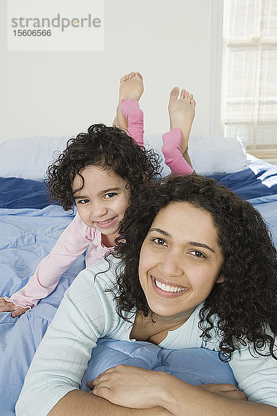 Porträt einer mittleren erwachsenen Frau mit ihrer auf dem Bett liegenden Tochter