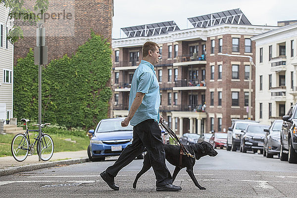 Mann mit Sehbehinderung geht mit seinem Diensthund spazieren