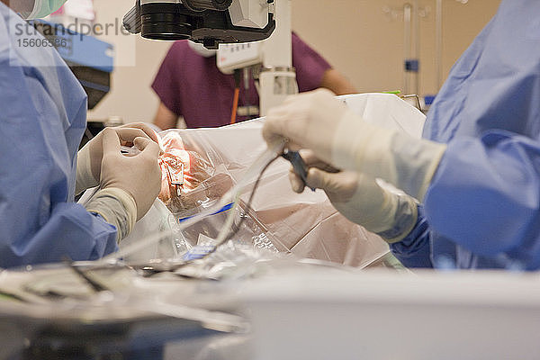 Chirurgische Technikerin mit Phako-Instrument und Arzt mit einer Spritze