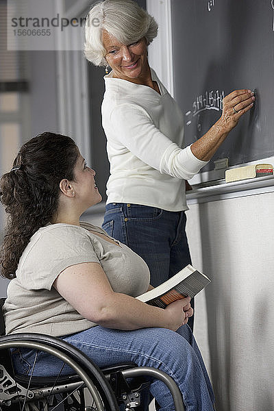 Eine Professorin und ein Student mit Spina Bifida im Klassenzimmer