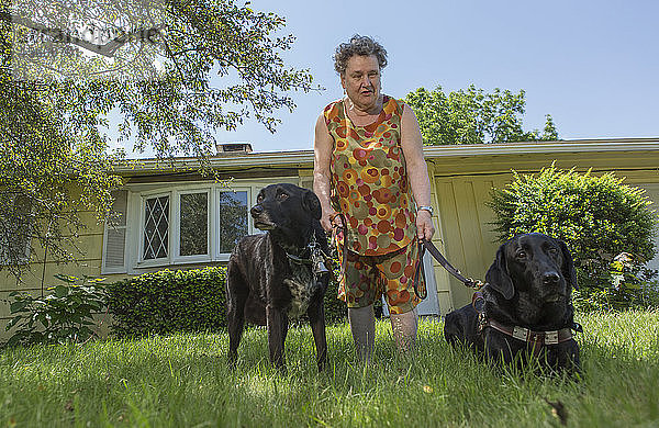 Blinde Seniorin mit ihren Diensthunden vor ihrem Haus