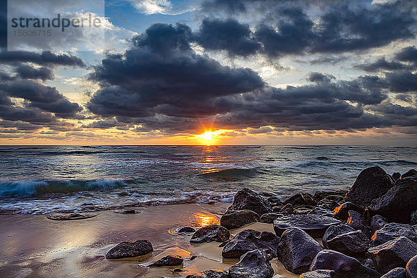 Sonnenaufgang über dem Pazifischen Ozean von den Felsen am Ufer des Lydgate Beach und dunklen Wolken am Himmel; Kapaa  Kauai  Hawaii  Vereinigte Staaten von Amerika