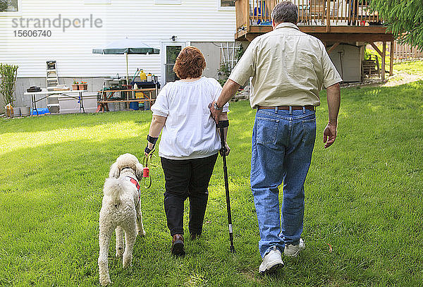 Frau mit RSD und ihr Diensthund mit Ehemann beim Spaziergang in ihrem Hinterhof