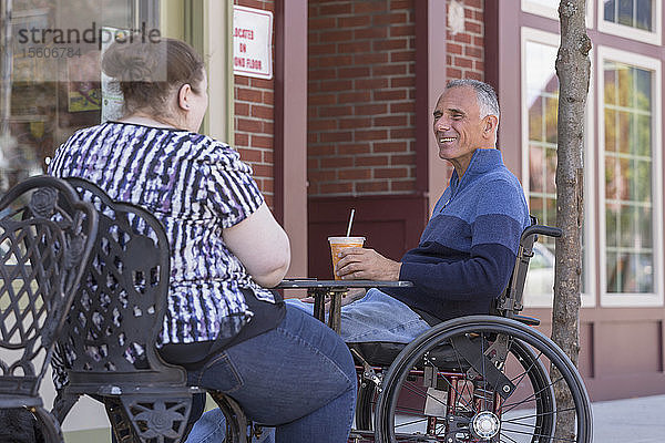 Frau mit Sehbehinderung sitzt mit ihrem Vater in einem Café