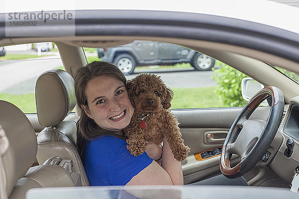 Junge Frau mit zerebraler Lähmung hält ihren Hund im Auto