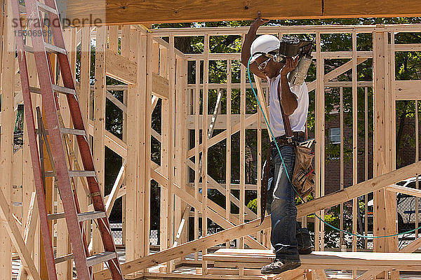 Ein Zimmermann steht auf einer Baustelle und hält eine Nagelpistole