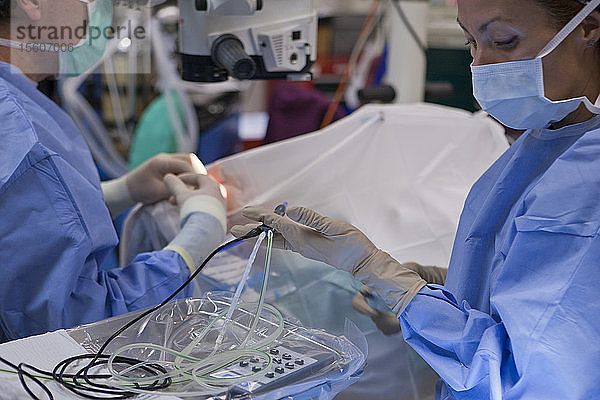 Chirurgische Technikerin reicht dem Arzt ein Phako-Handstück während einer Kataraktoperation