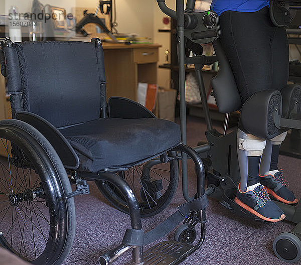 Eine Frau mit einer Rückenmarksverletzung setzt sich an ihren Schreibtisch  damit sie aufstehen kann