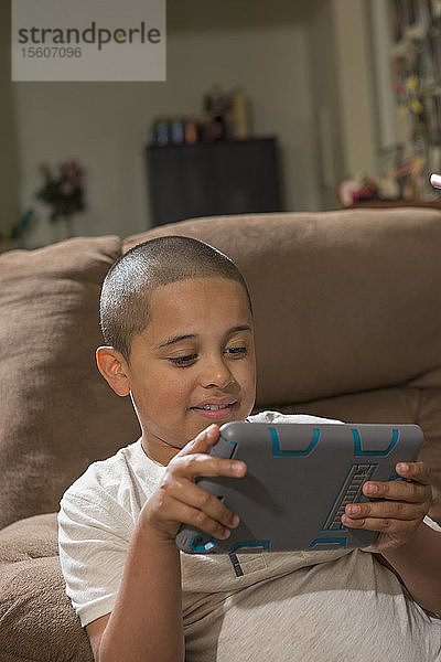 Hispanischer Junge mit Autismus spielt zu Hause ein elektronisches Spiel
